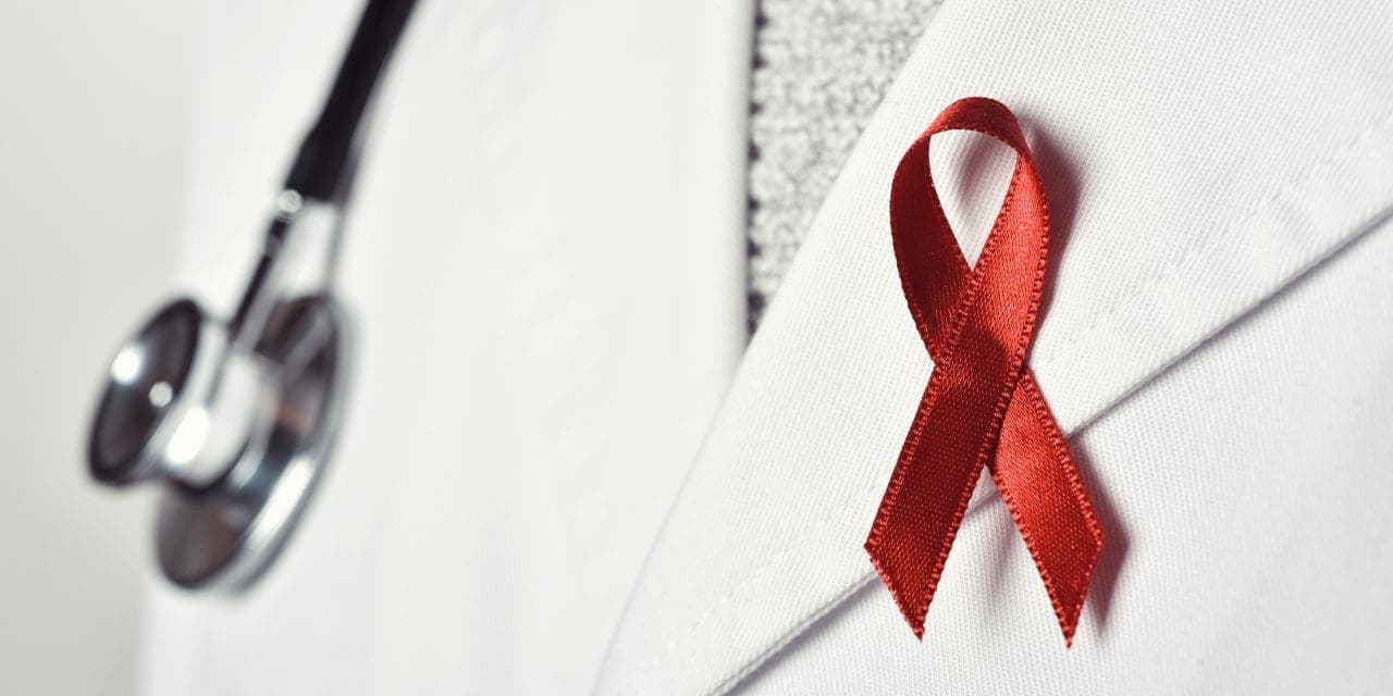 closeup person's chest part showing a stethoscope and red ribbon