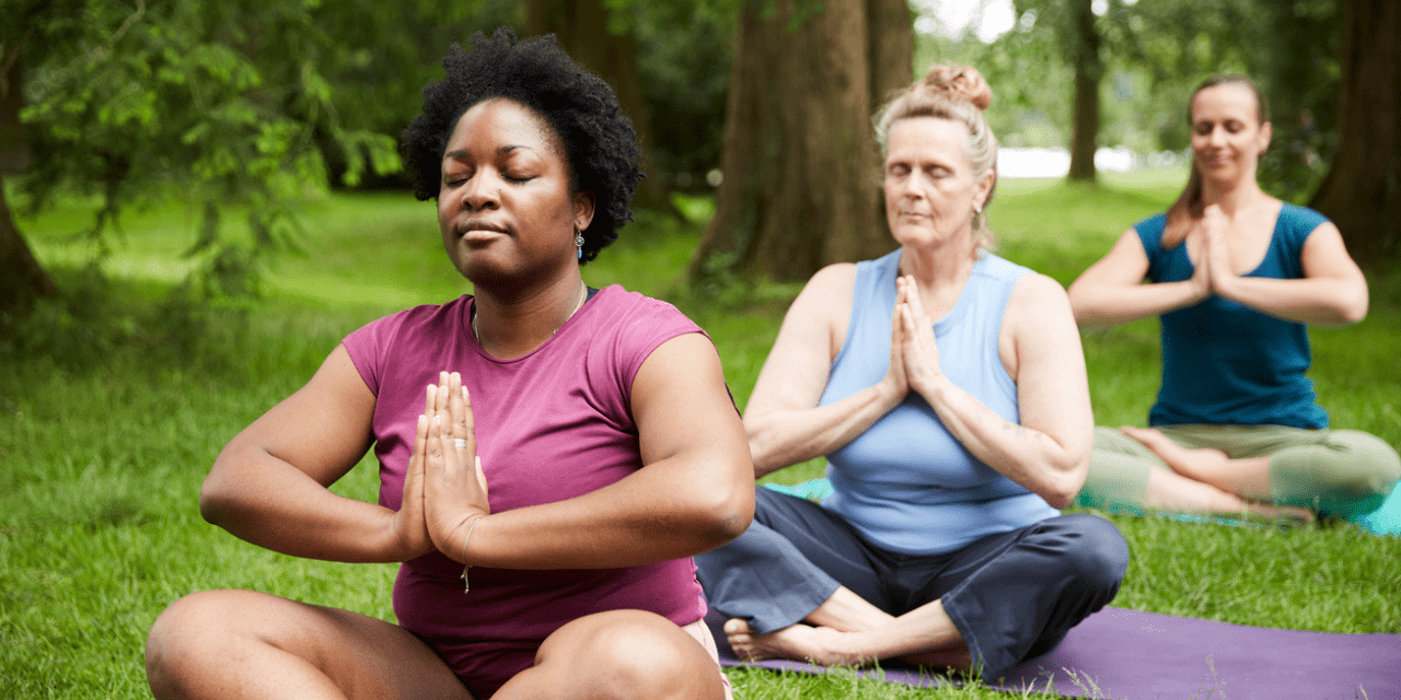 three women practicing yoga outside